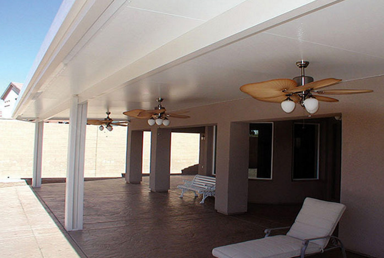 Patio cover in San Antonio with insulated aluminum roof panels and ceiling fans attached to home.