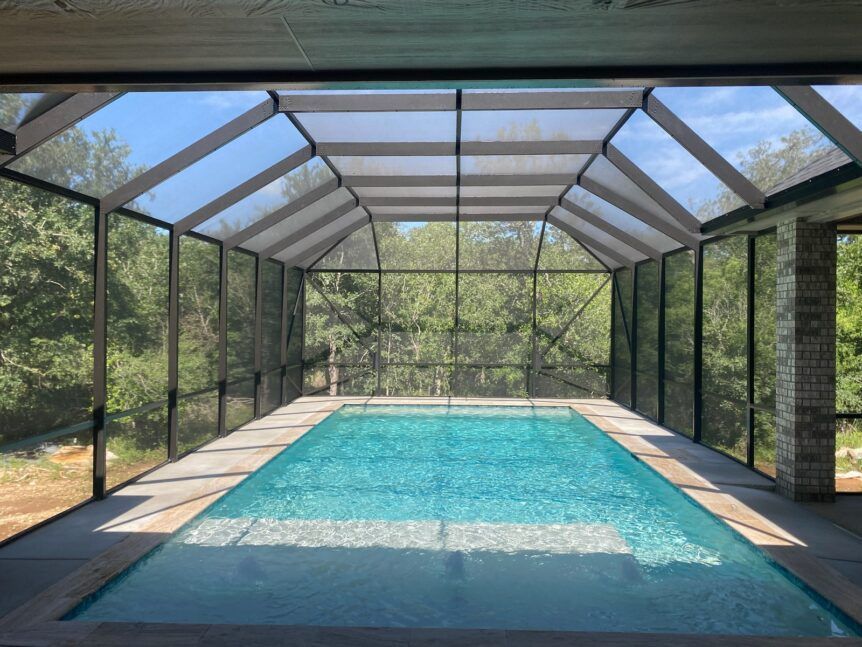 Backyard pool enclosure with cedar trim and UV-resistant screens in New Braunfels TX