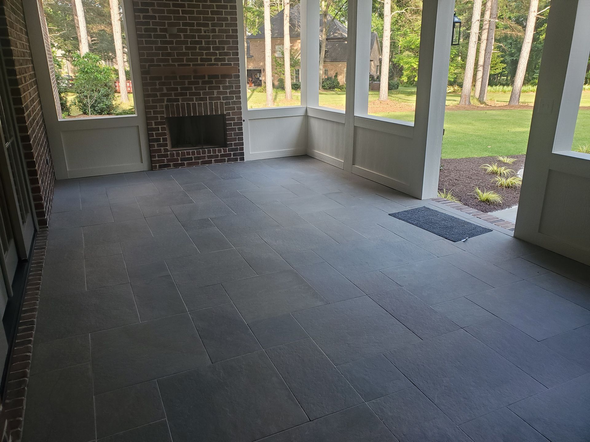 A screened in porch with a fireplace and a brick wall