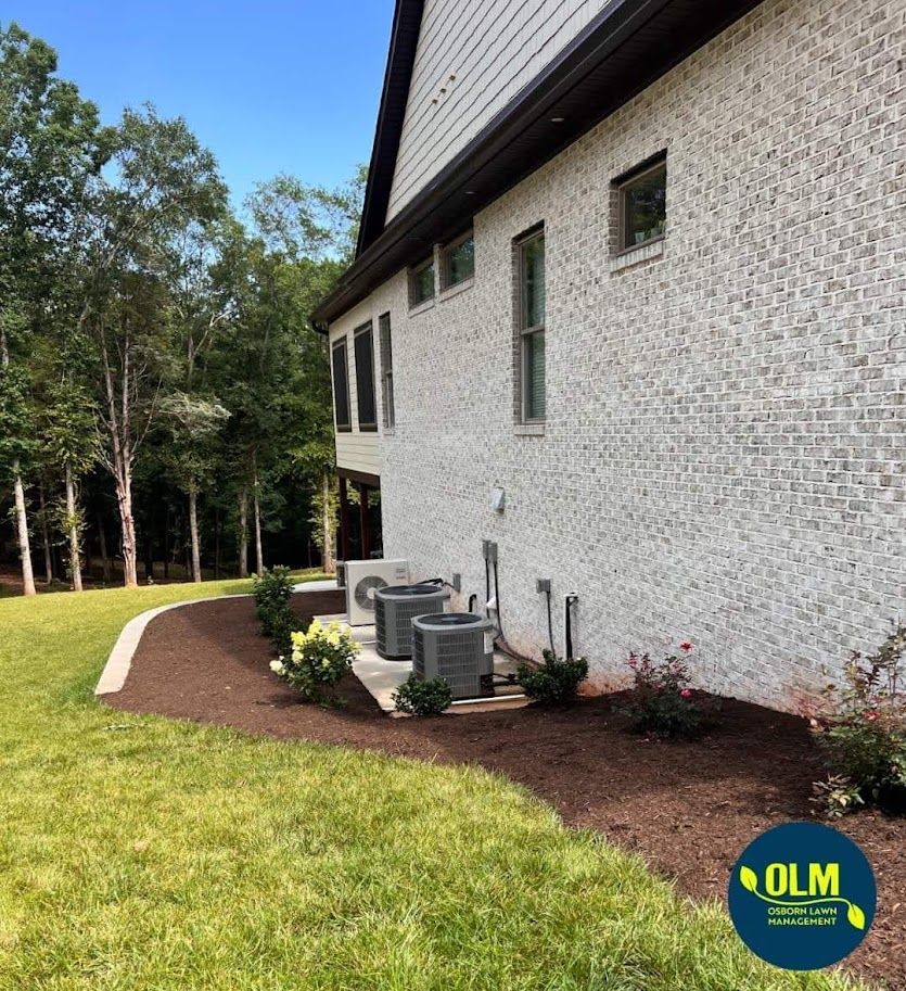 fresh plantings installed by a white brick house with a lot of windows and air conditioners