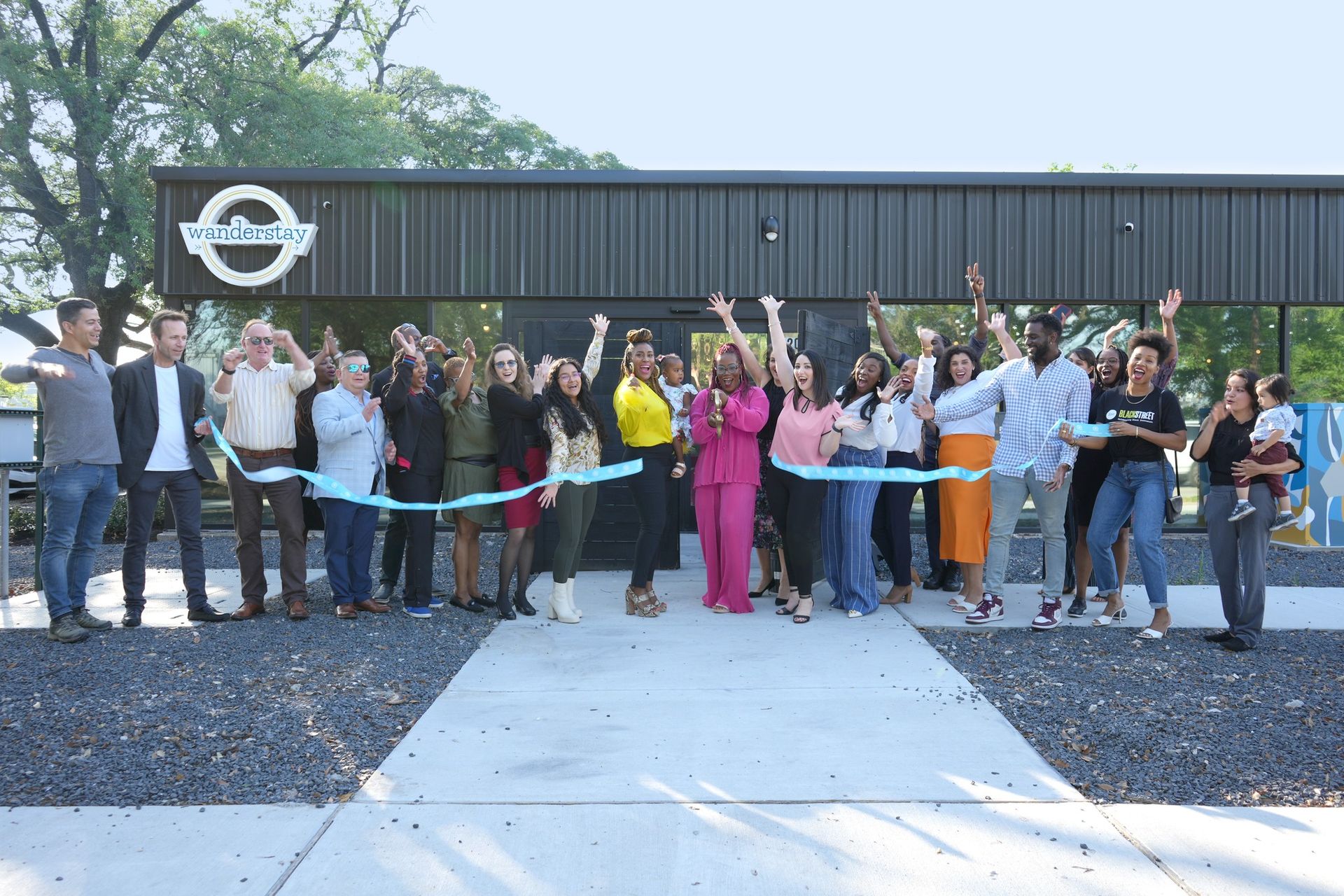 Personas cortando una cinta azul frente a un edificio con un cartel que dice 
