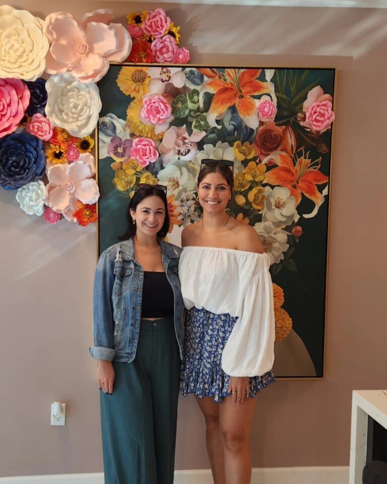 Luxurious modern lounge with blue couches, a kitchen, and colorful wall art.