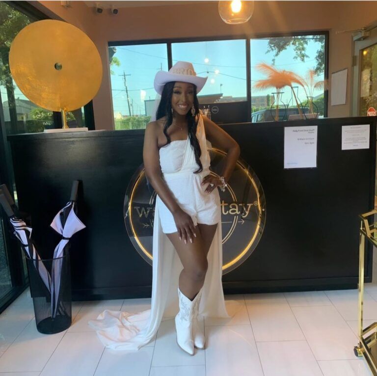 Luxurious lounge with blue velvet sofas, gold chairs, and vibrant mural. Large windows overlook a patio.