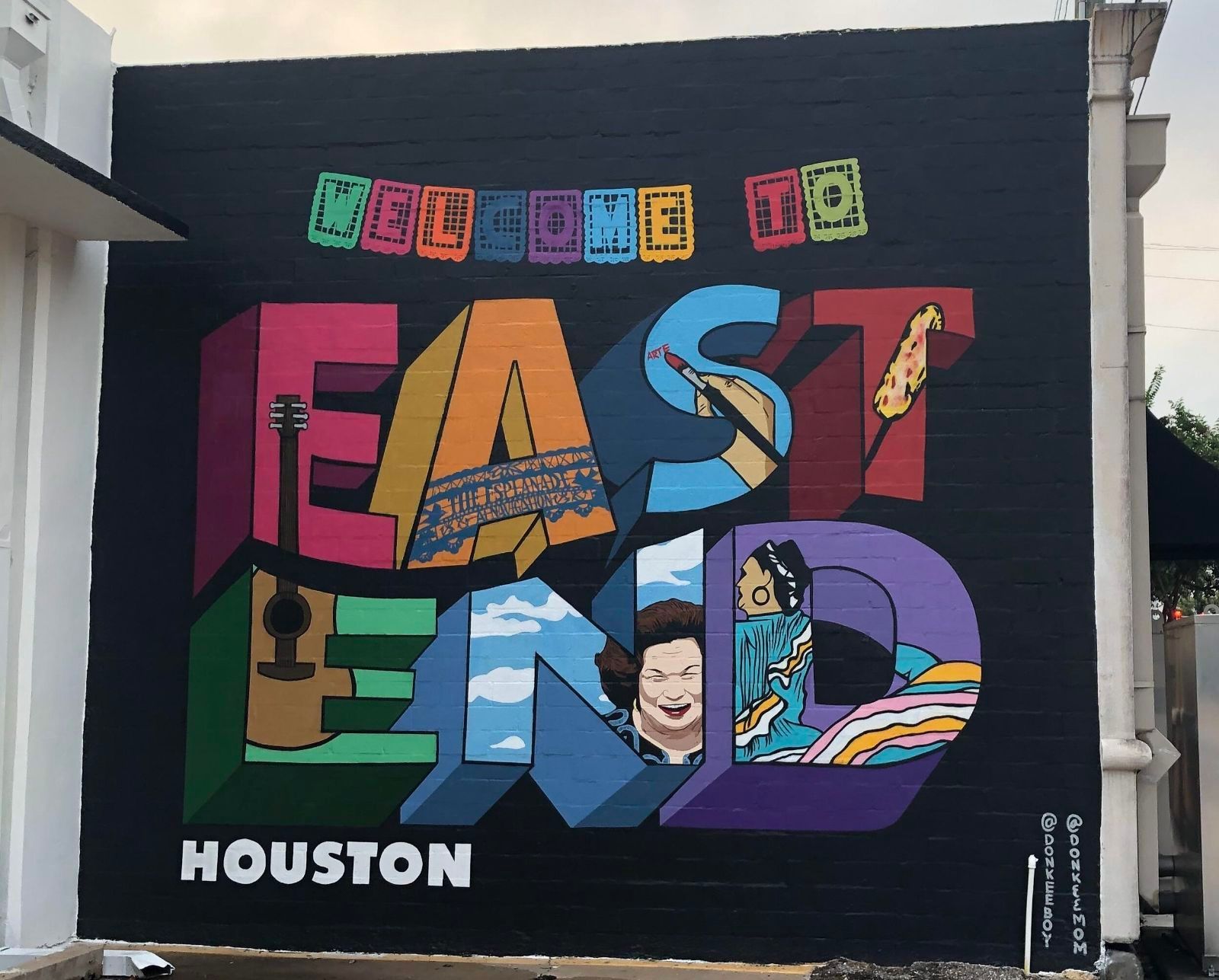 Luxurious modern lounge with blue couches, a kitchen, and colorful wall art.