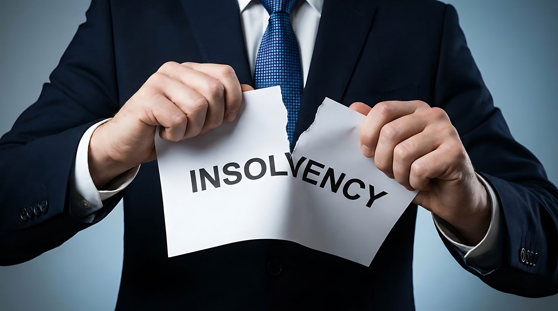 Businessman tearing 'Insolvency' paper, symbolizing financial freedom and resolution from debt crisis
