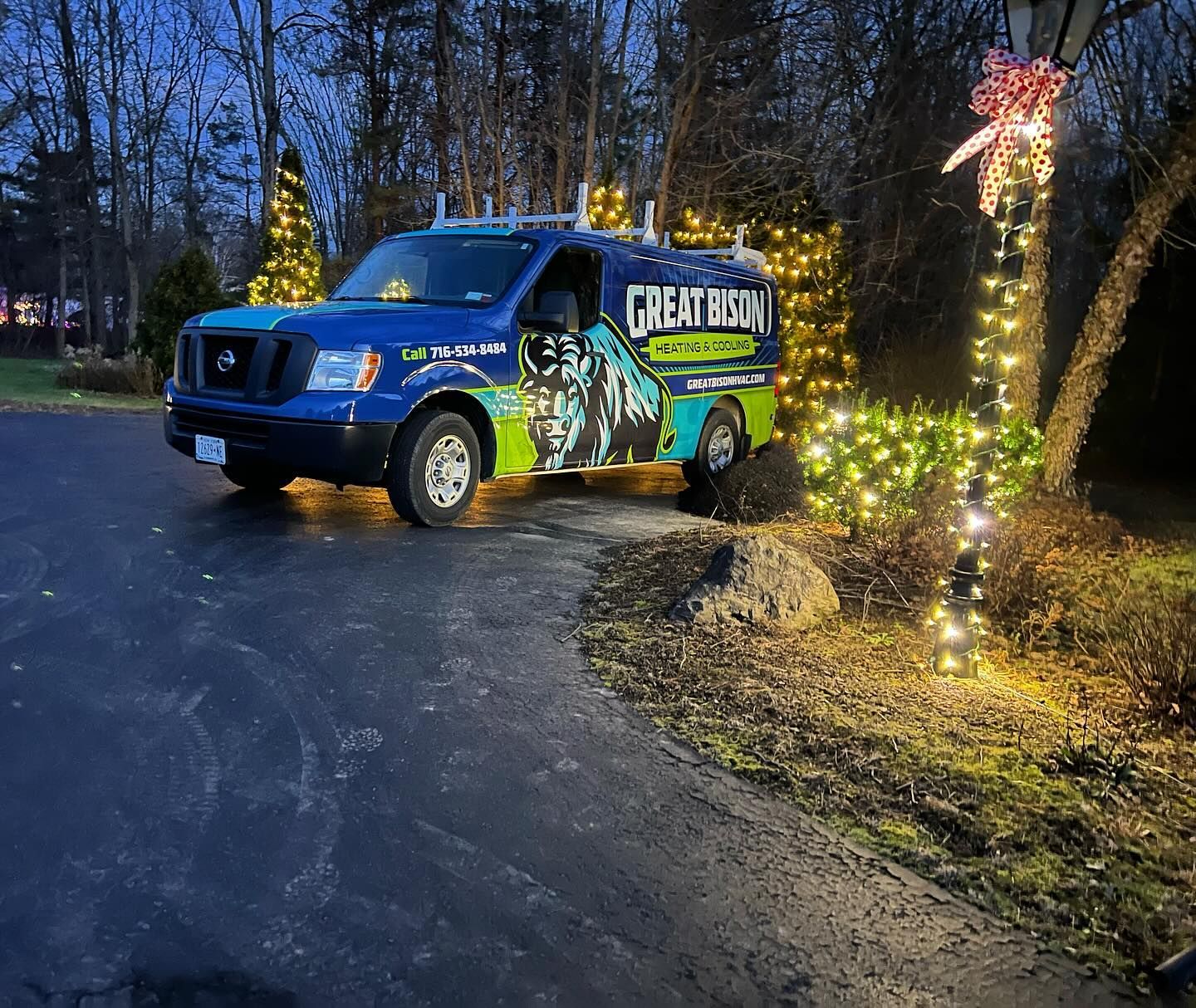 Blue service van with Christmas lights; parked on a driveway with a tree, the words 
