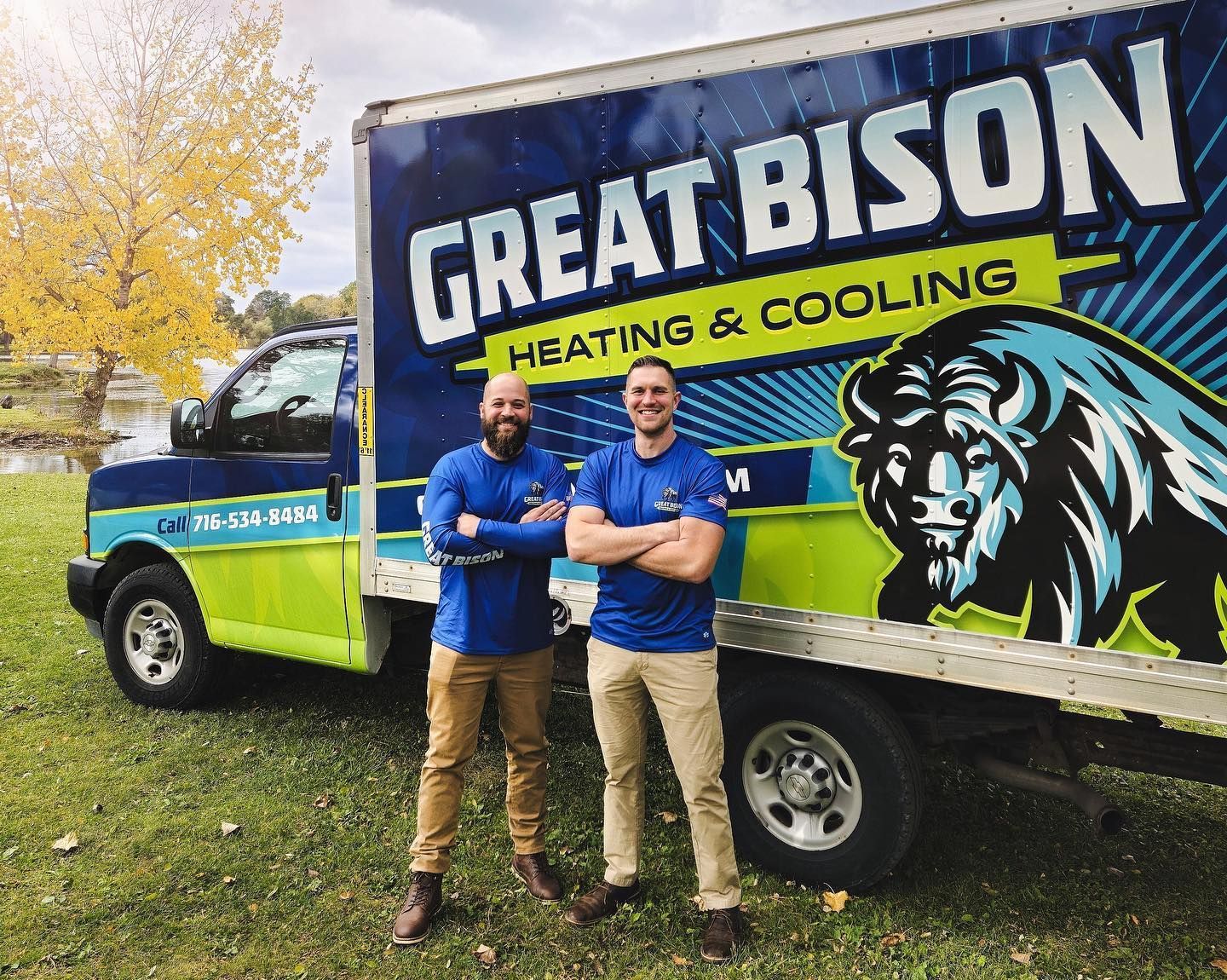 Two men in front of a Great Bison Heating & Cooling truck. Men have crossed arms, smiling. Outdoors, sunny.