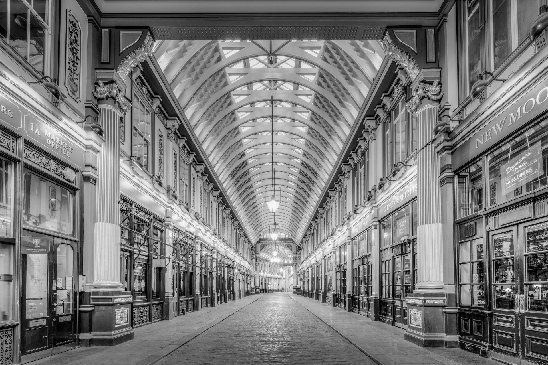 A black and white perspective view of Leadenhall Market, featuring a high, vaulted glass ceiling and classic storefronts.