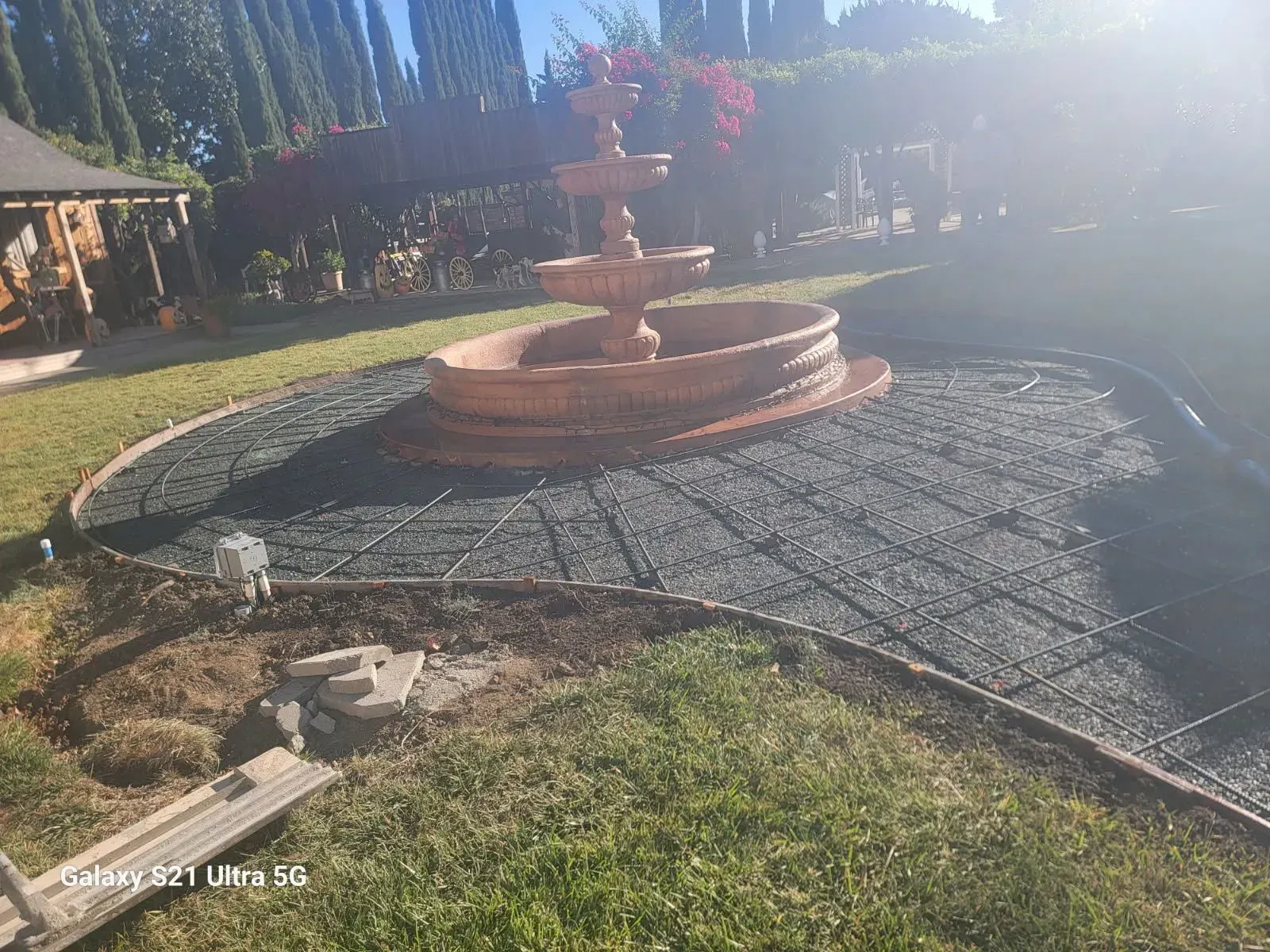 A fountain is sitting in the middle of a lush green field.