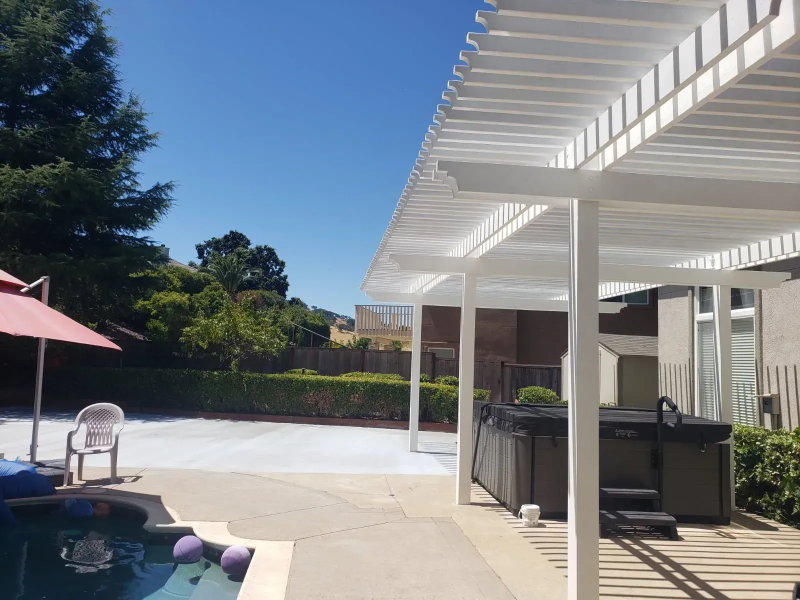 A swimming pool with a hot tub under a pergola