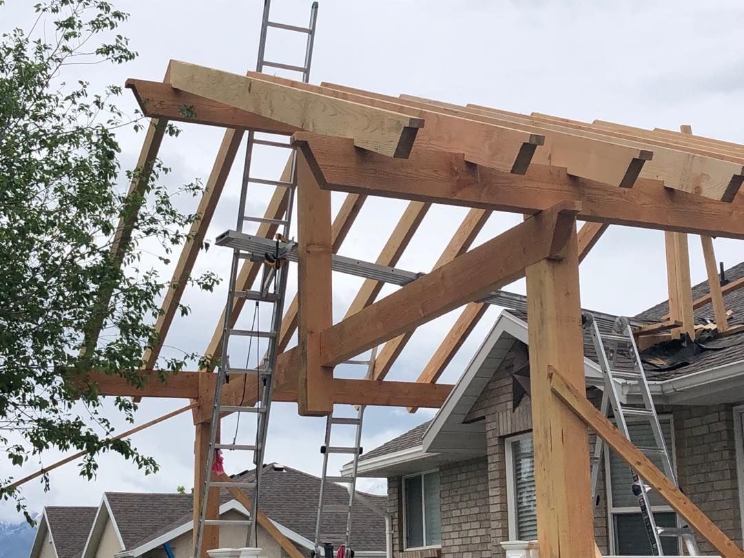 Wooden pergola under construction next to a house with ladders.