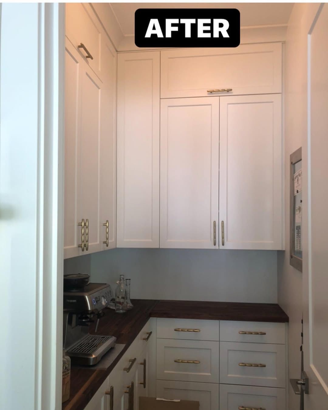 White pantry cabinets with a wood countertop and espresso machine, 