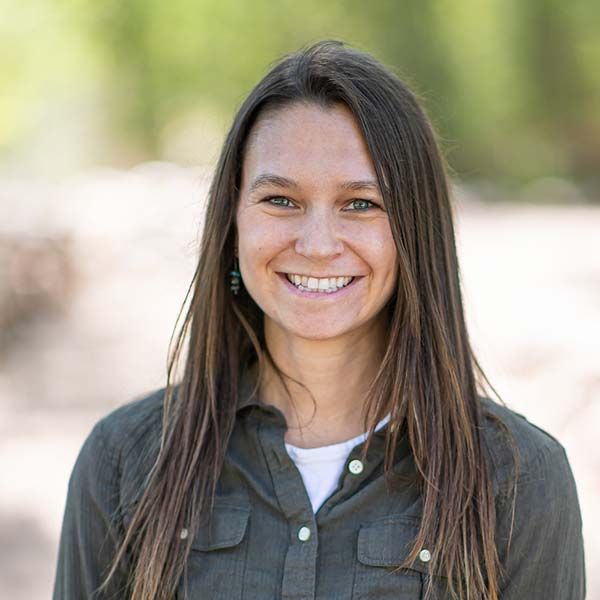 A woman in a green shirt is smiling for the camera.