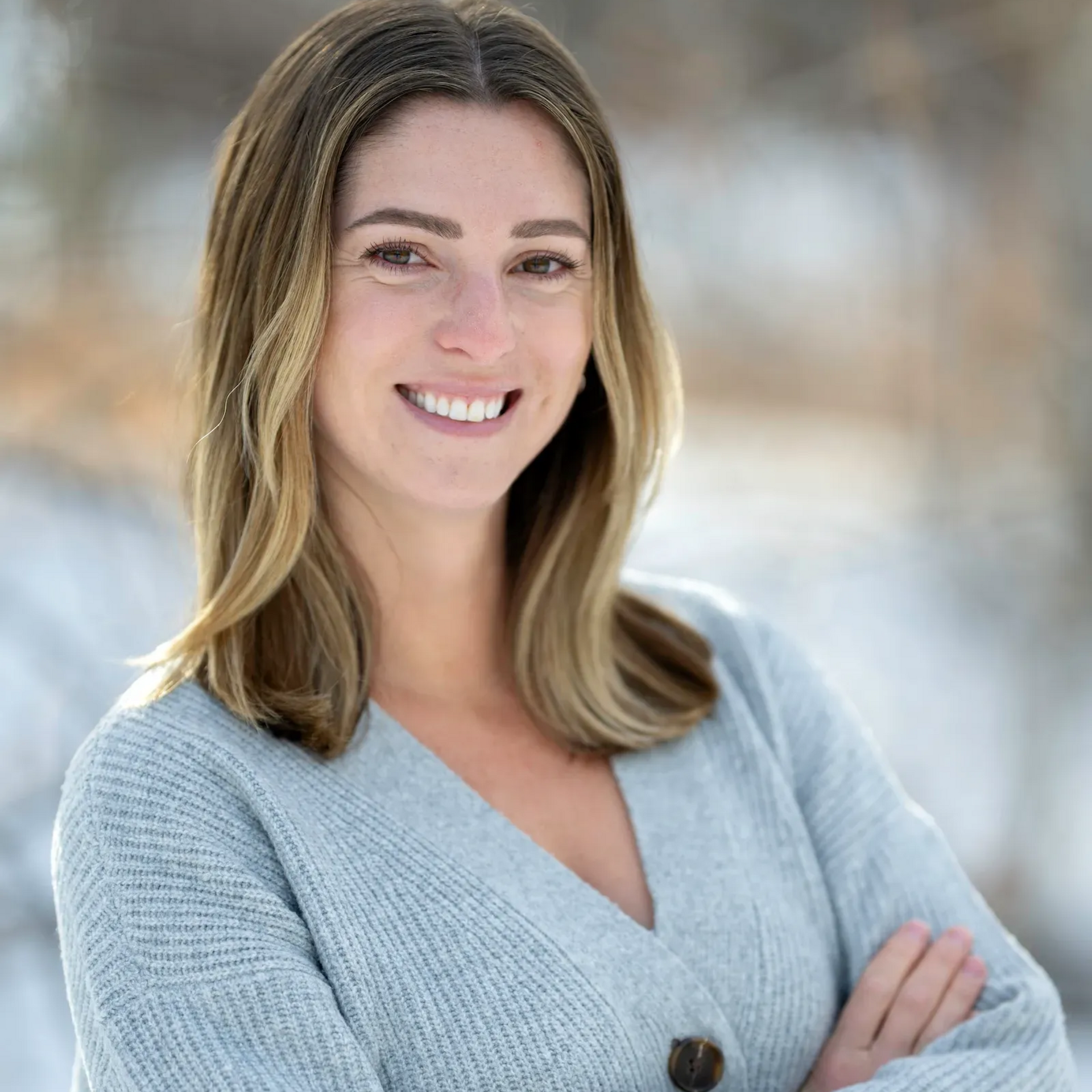 A woman with long hair is smiling for the camera while wearing a white shirt.