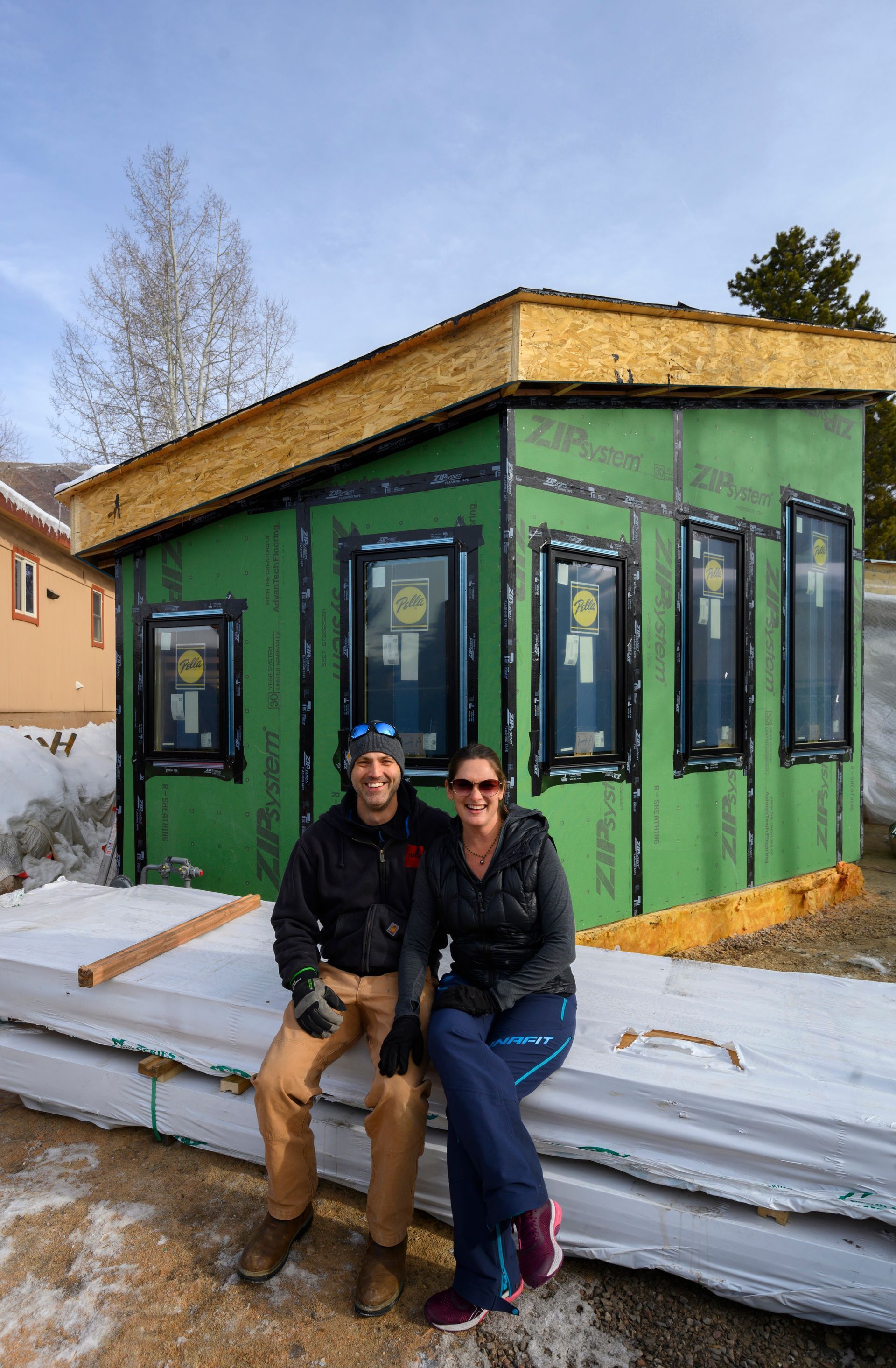 A man and a woman are sitting in front of a house under construction.