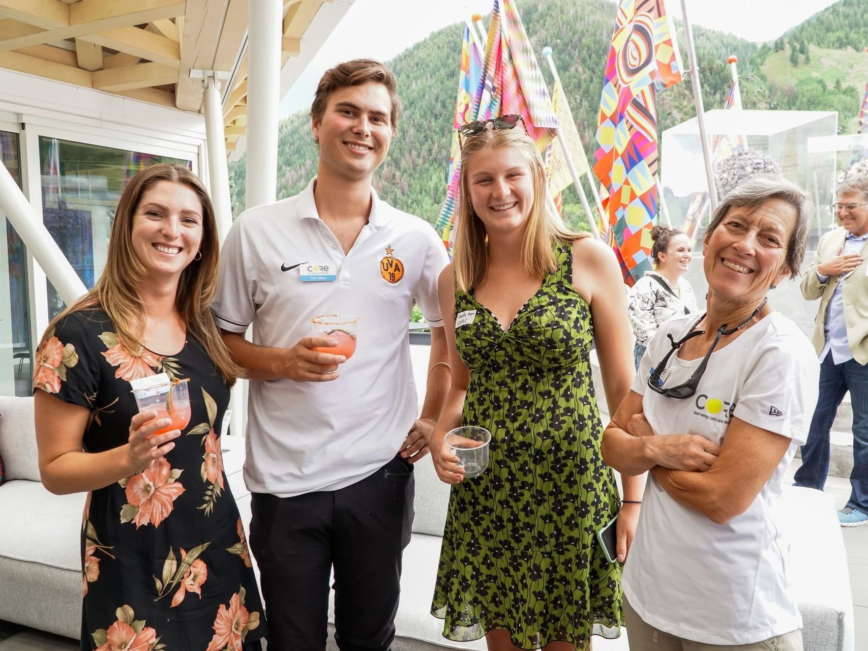 A group of people is posing for a picture while holding drinks on an outdoor patio.
