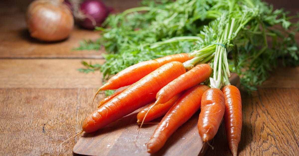 A bunch of carrots sitting on top of a wooden cutting board.