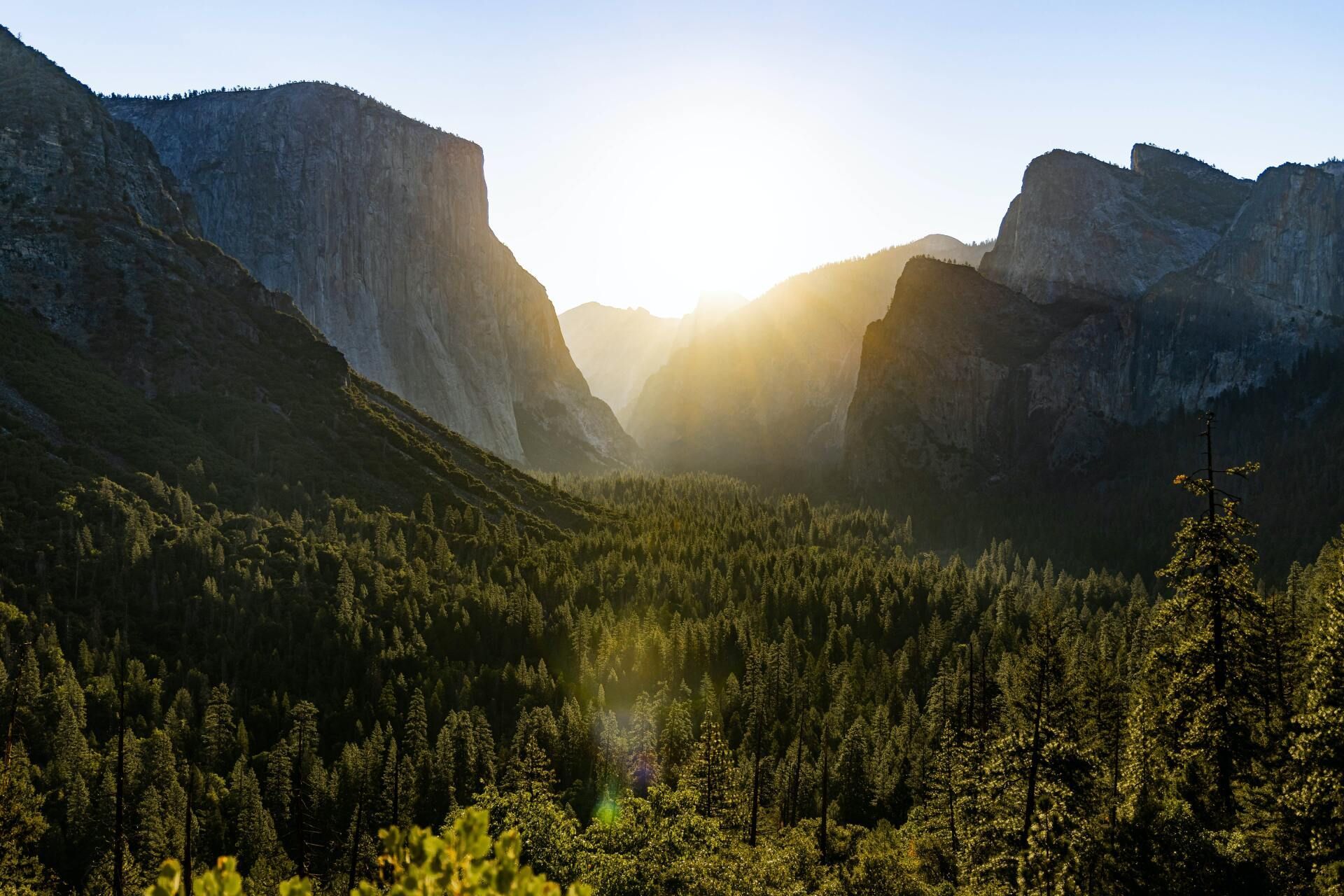 The sun is shining through the mountains in yosemite national park.