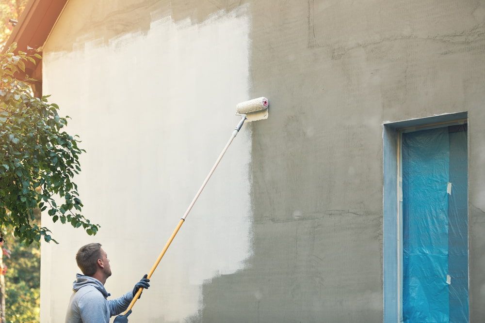 A Man Is Using A Paint Roller To Paint A Wall — Peter the Painter In Evatt, ACT