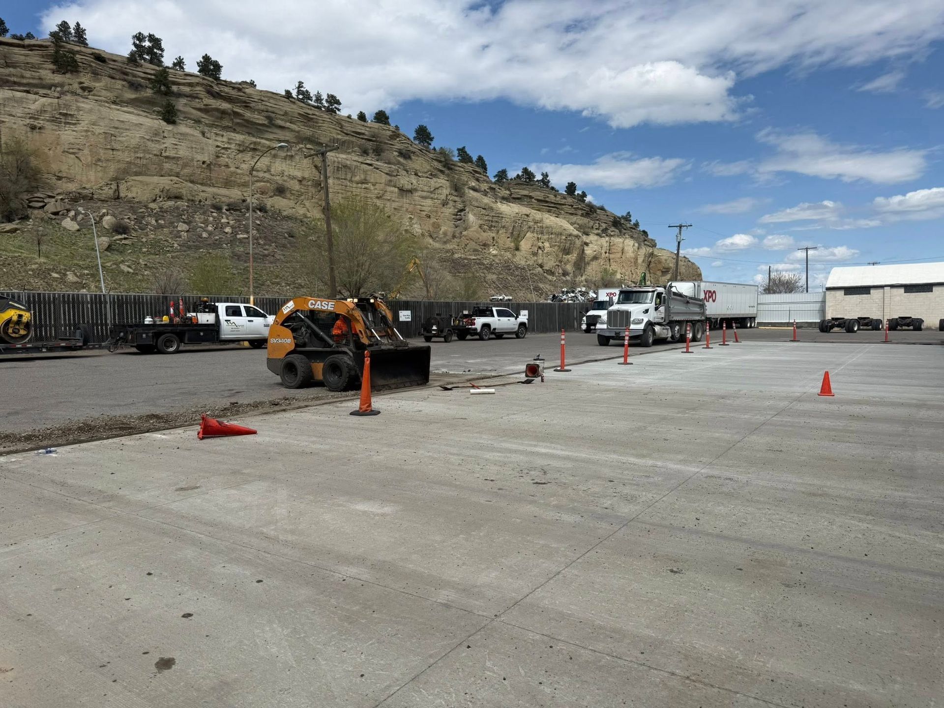 A row of construction vehicles are parked in a parking lot