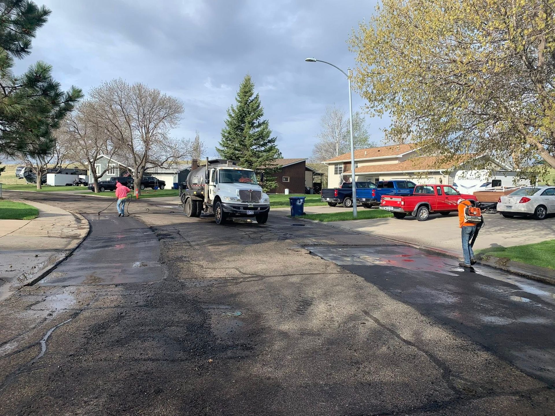 A dump truck is driving down a street in a residential neighborhood.
