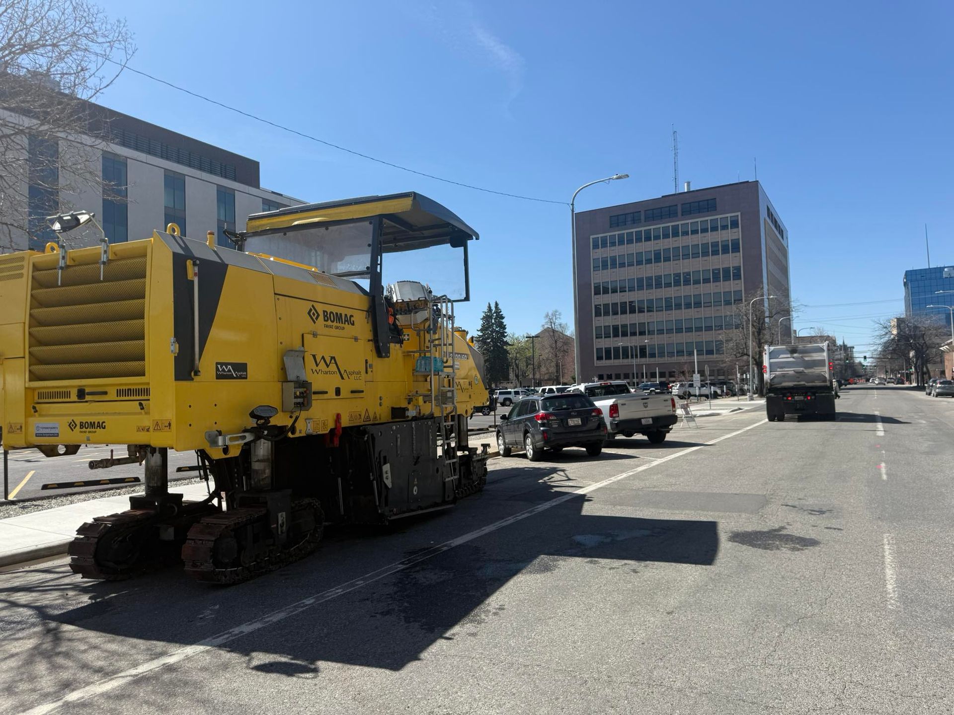 A yellow construction vehicle is parked on the side of a city street.