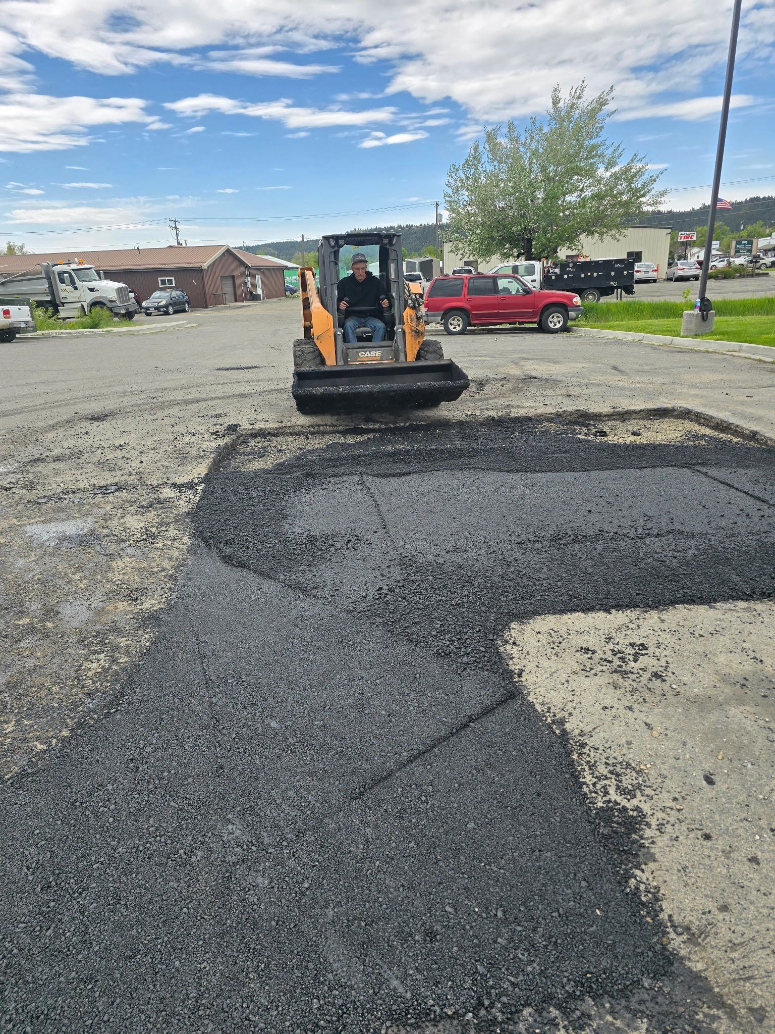 A man is driving a bulldozer in a parking lot.