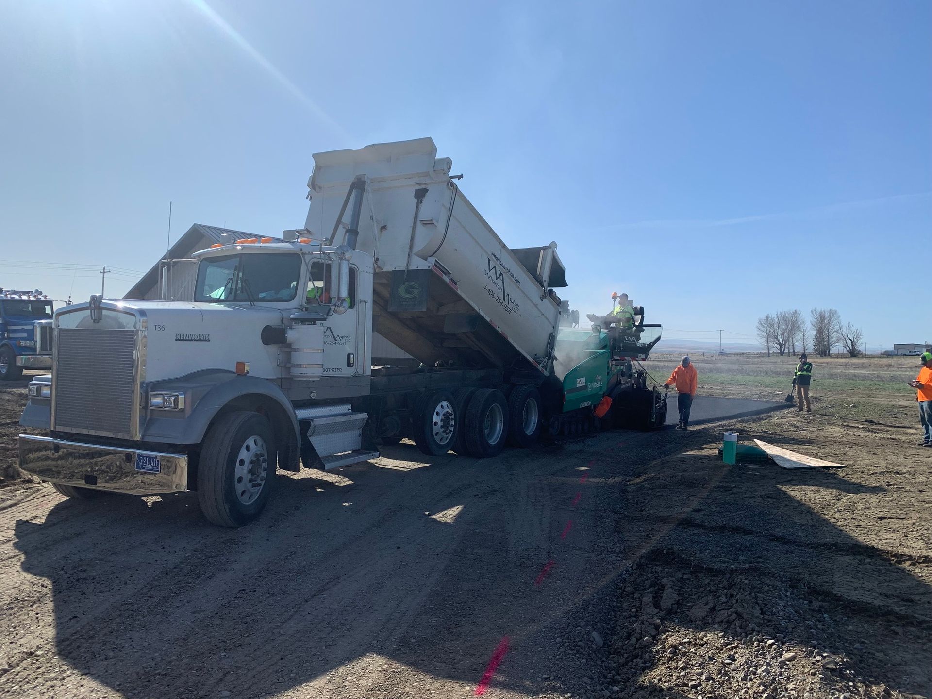 A dump truck is parked on the side of a dirt road.
