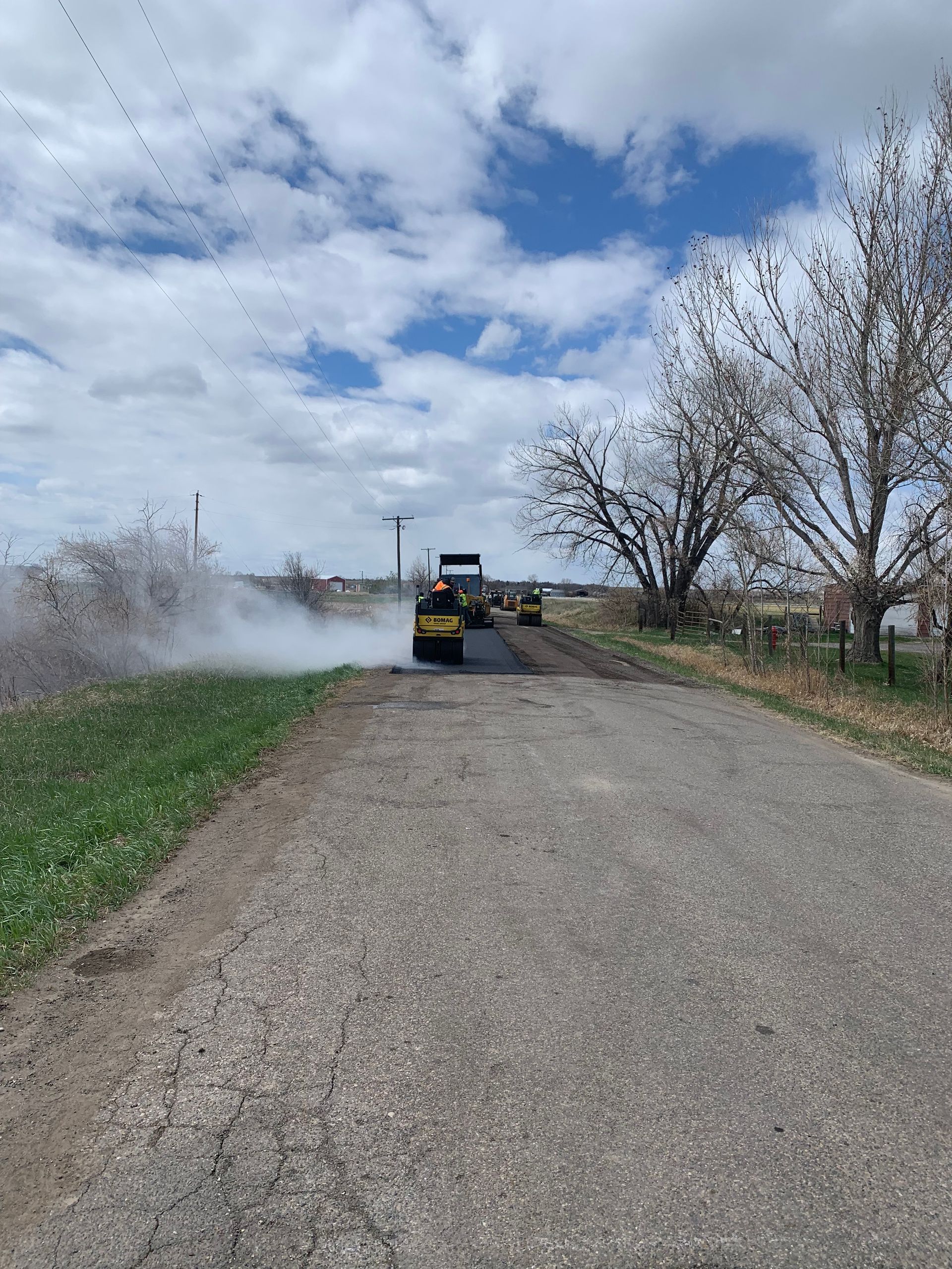 A truck is driving down a dirt road next to a field.