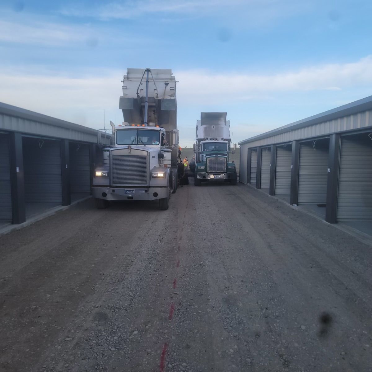 Two trucks are parked next to each other on a dirt road