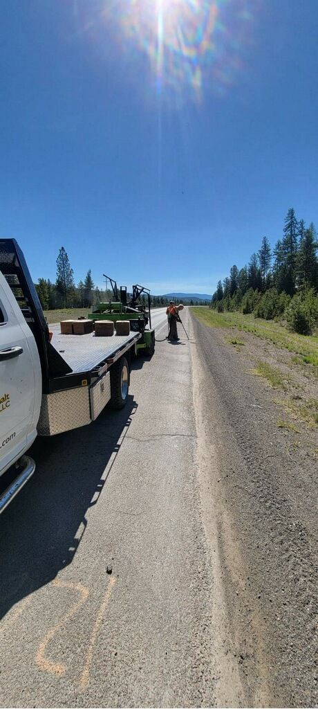 A tow truck is sitting on the side of a dirt road.