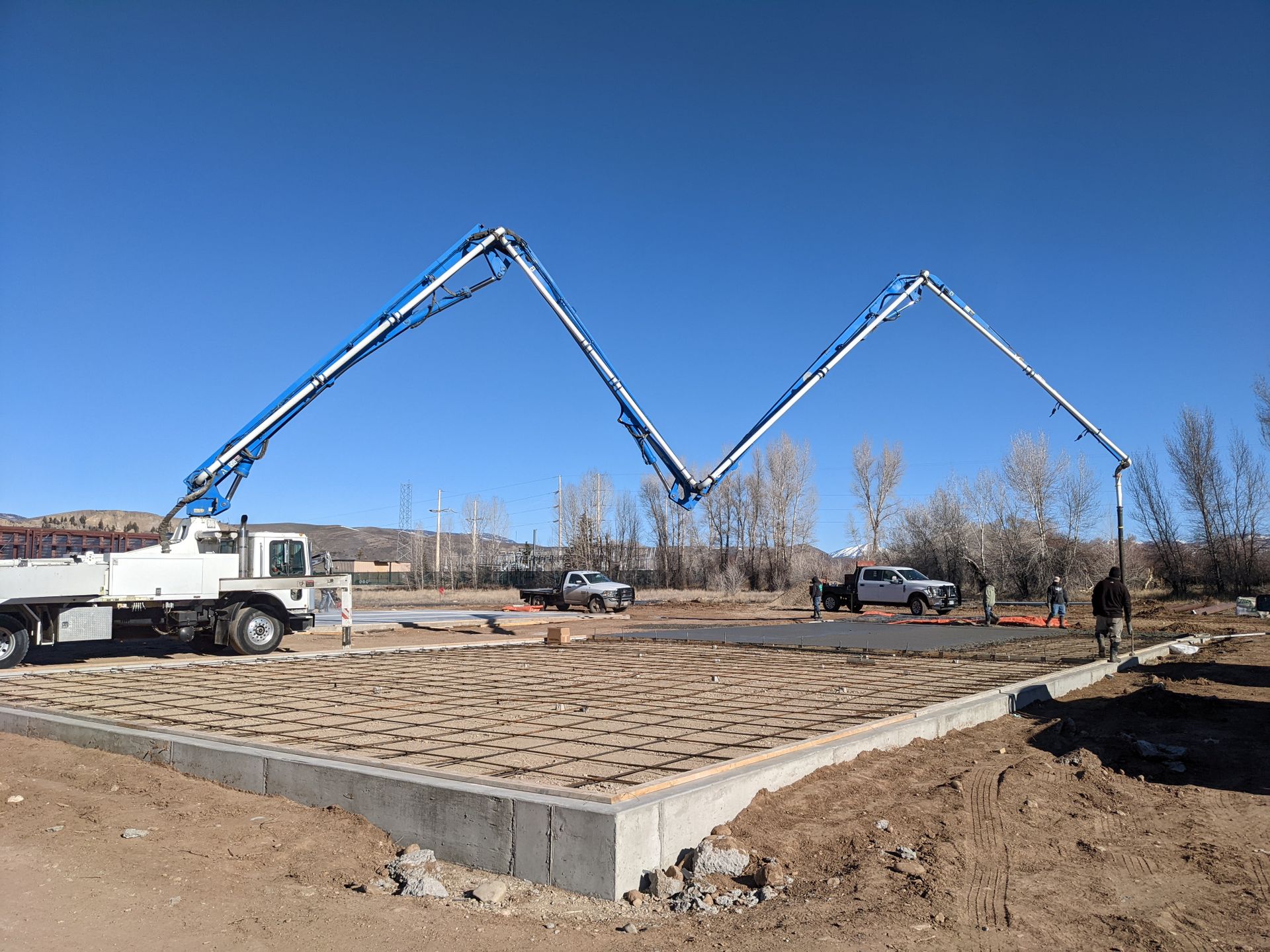 sparta white and blue concrete boom truck with boom extended pouring foundation