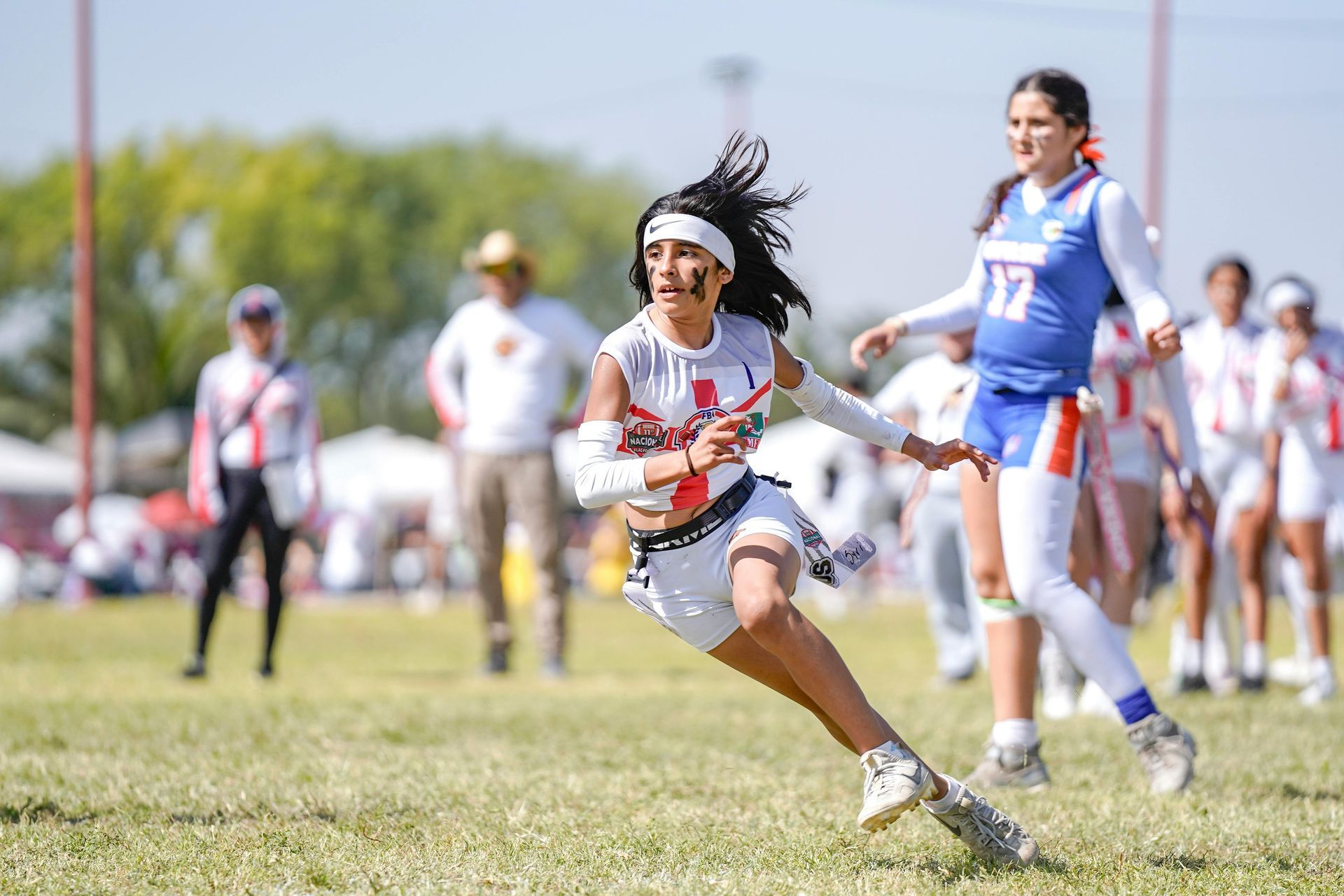 Football players huddle around a football, reaching hands together, blue sky backdrop.