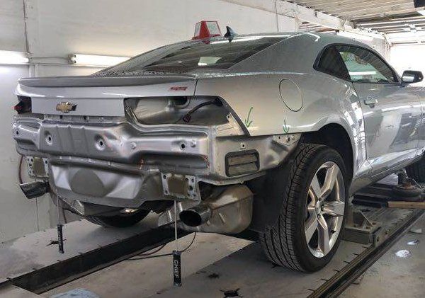 A silver car is being repaired in a garage.
