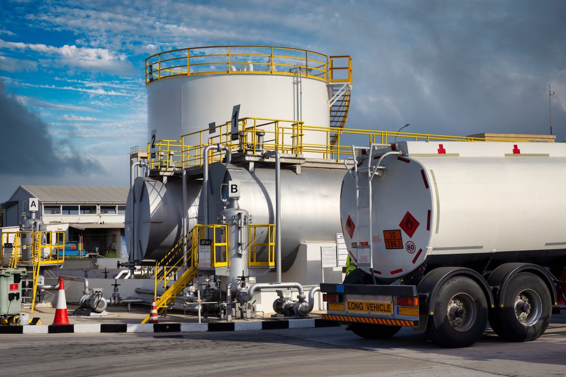 A tanker truck is parked in front of a large tank.