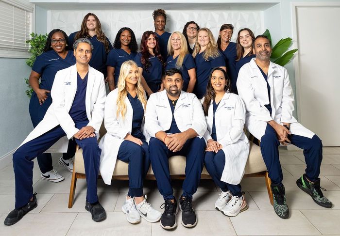 A group of doctors and nurses are posing for a picture while sitting on a couch.