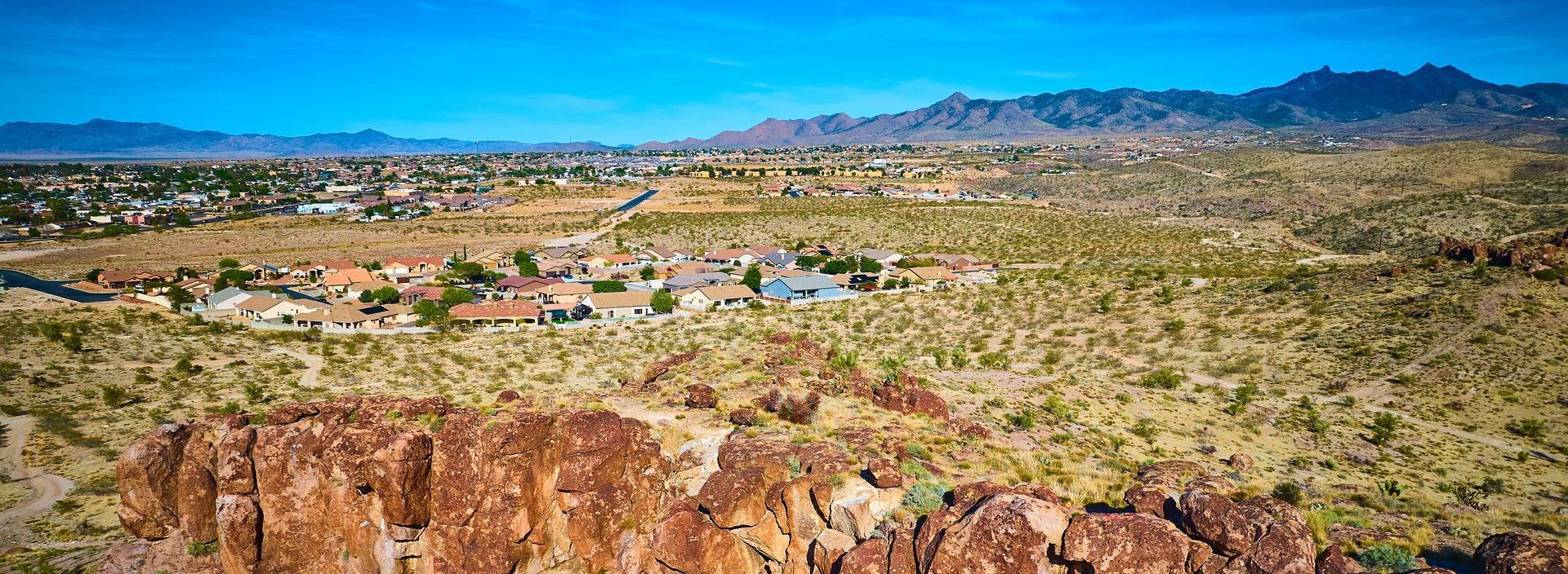 An aerial view of a desert landscape with a city in the distance.