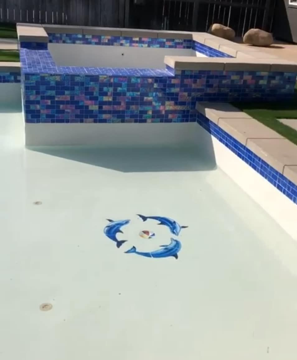 Blue tiled spa and pool with dolphin tile mosaic.