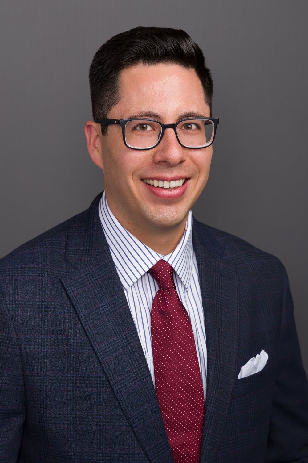 Man in suit and glasses smiling, professional portrait.