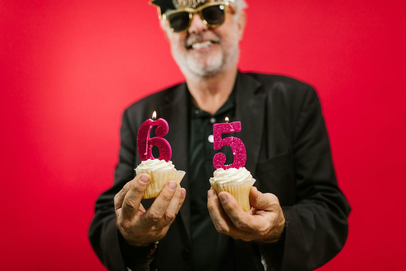 Smiling man with sunglasses holding cupcakes with