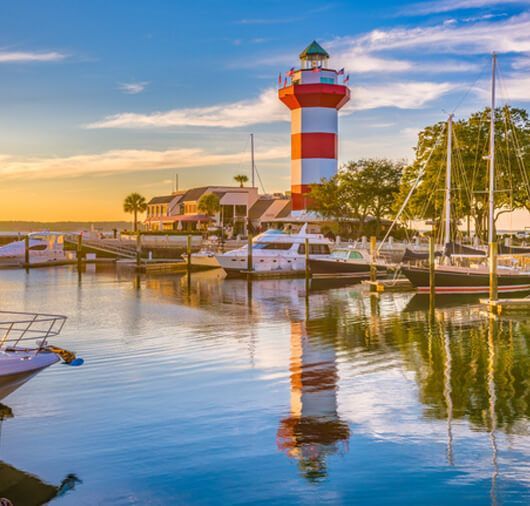 A red and white lighthouse sitting in the middle of a harbor surrounded by boats.