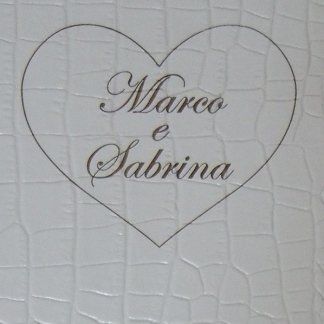 Superficie in pelle color perla con un' incisione colo oro con due nomi inseriti in un cuore