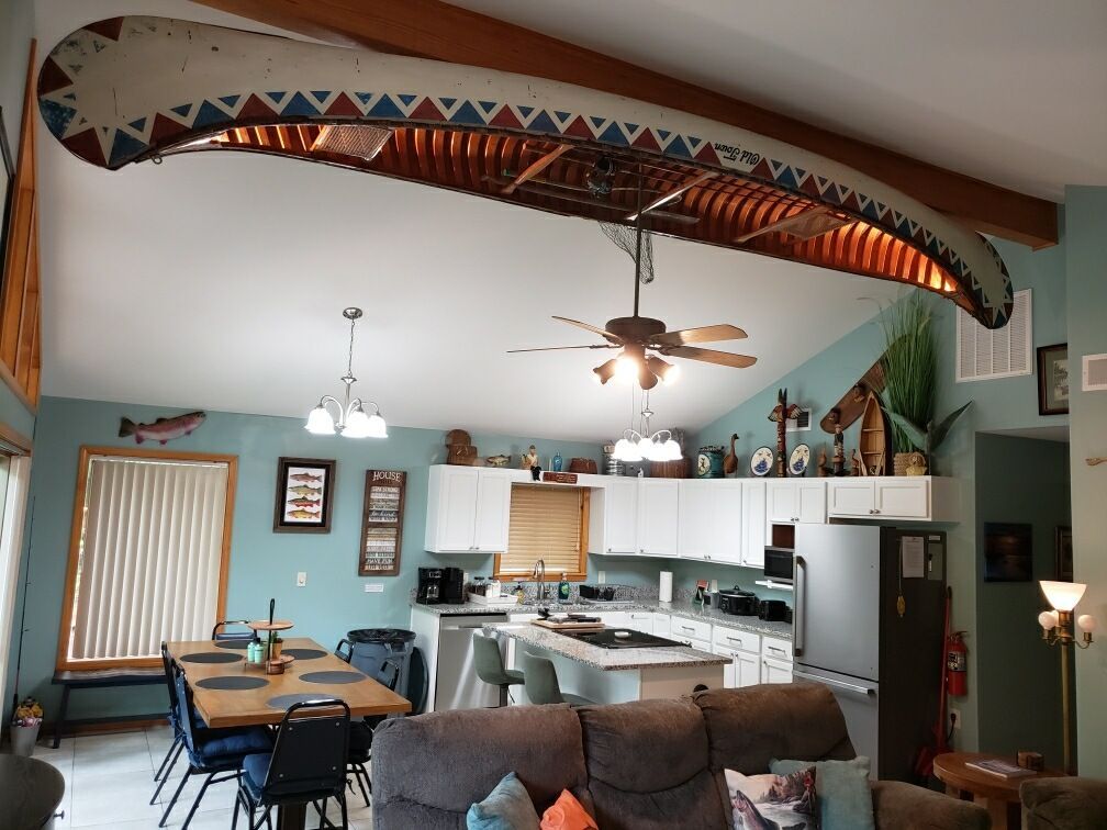 Living room with canoe decor on ceiling, kitchen, dining table, and sofa.