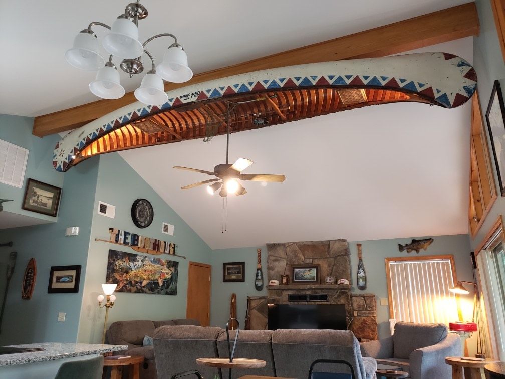 Living room with a canoe suspended from the ceiling; a fireplace, couches, and decorative items.