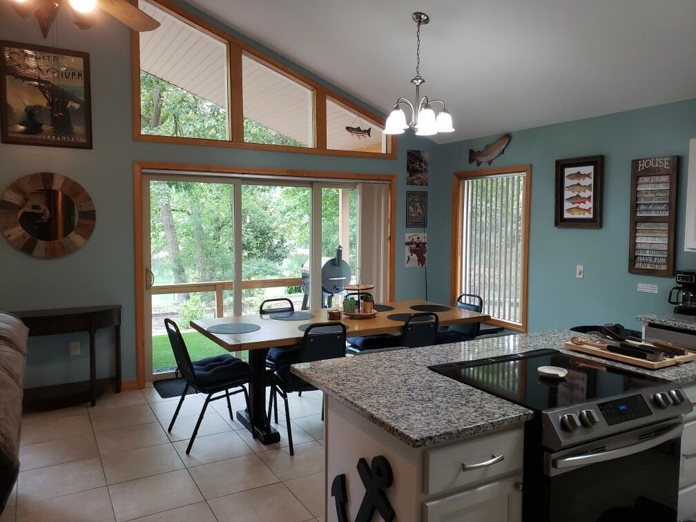 Kitchen with teal walls, granite countertops, and a dining table with outdoor views.