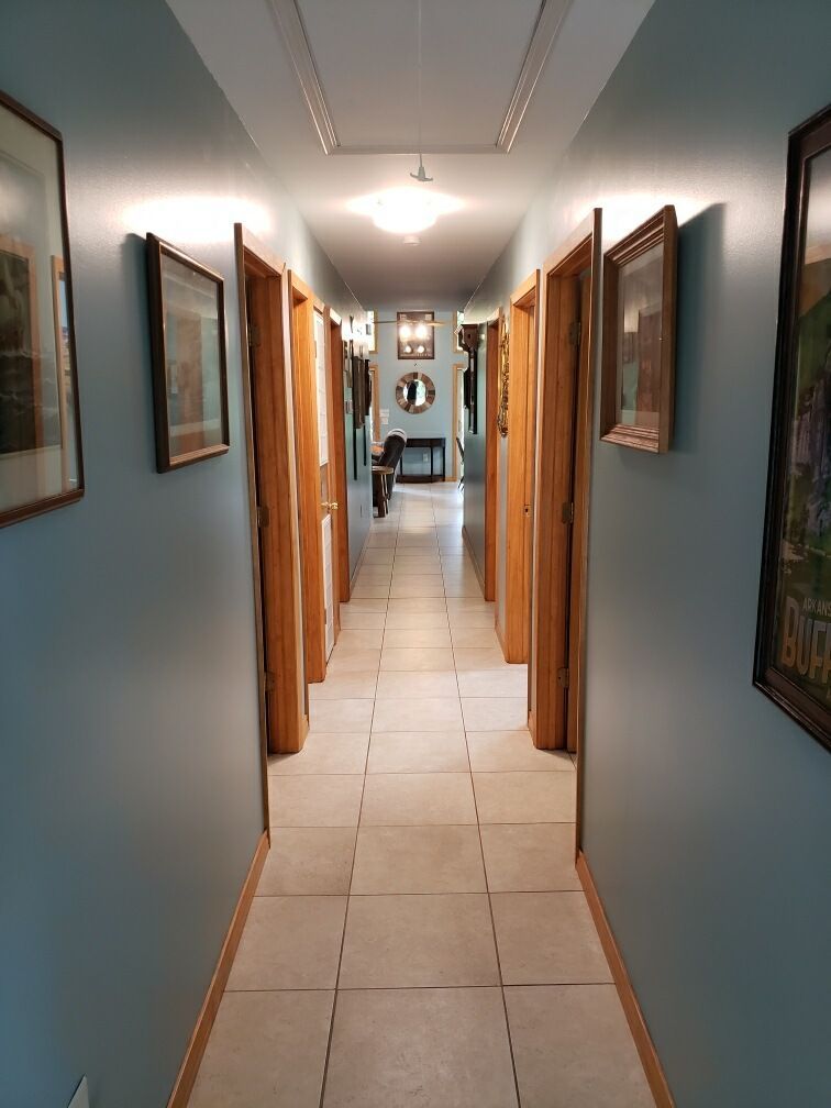 Long hallway with light blue walls, tiled floor, and multiple closed wooden doors.