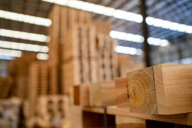 A close-up of wooden boards with large stacks of wooden crates in the background in a warehouse.
