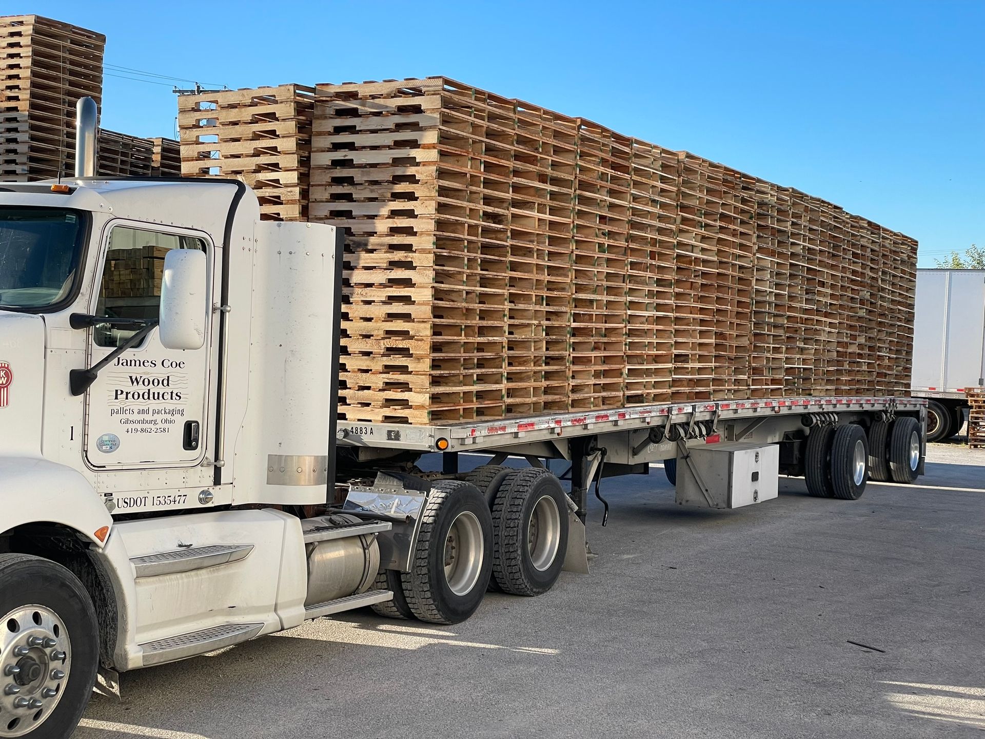 A semi truck with a trailer full of wooden pallets