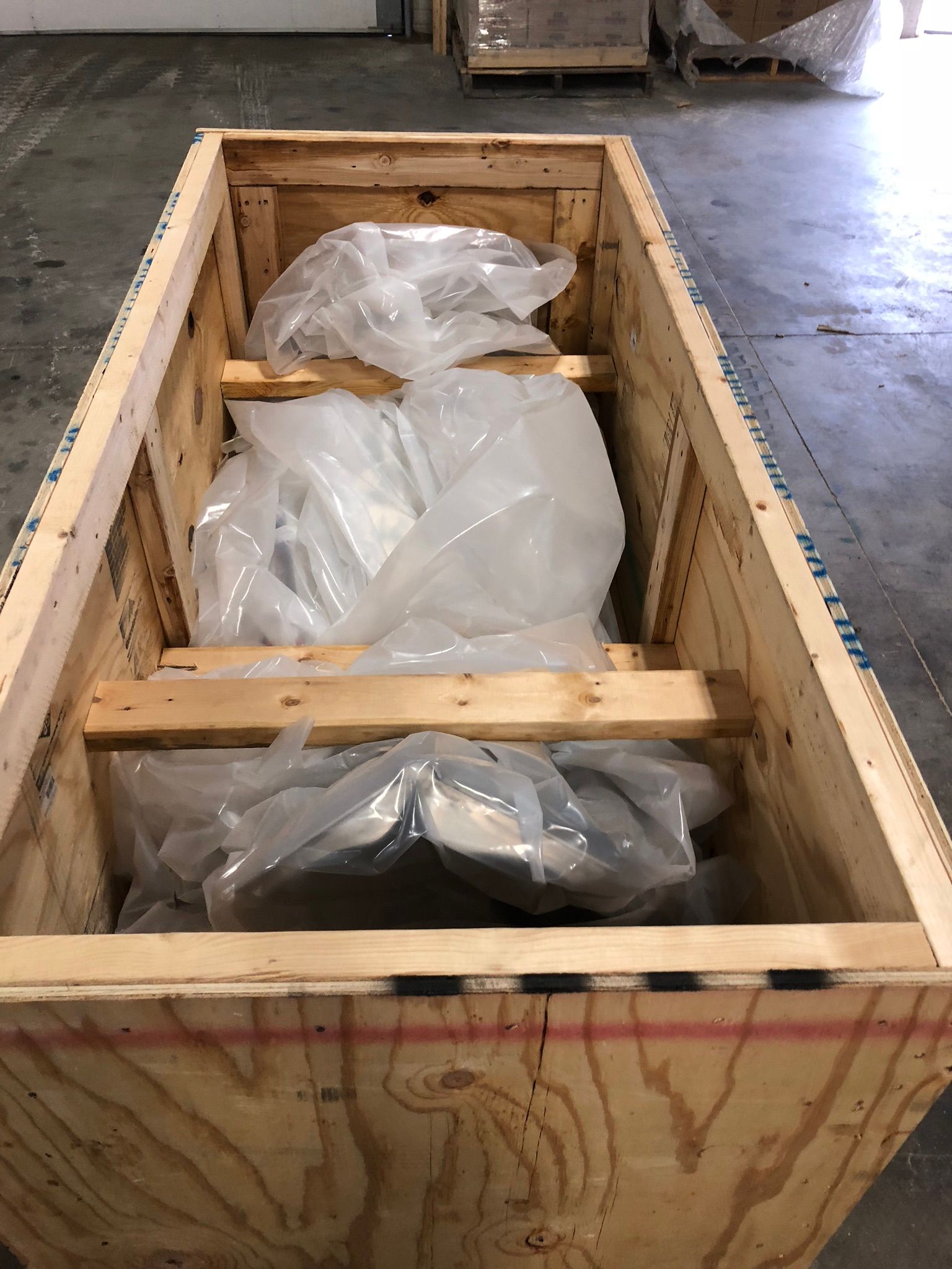 A wooden box filled with plastic bags in a warehouse