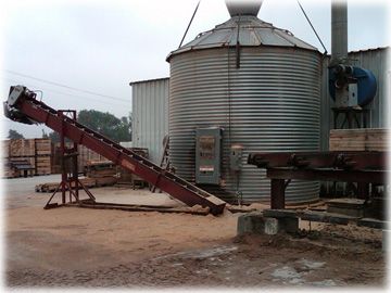 A metal silo with a conveyor belt attached to it